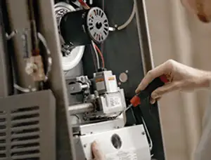 Furnace repair technician inspecting internal components and wiring in Andover, MA